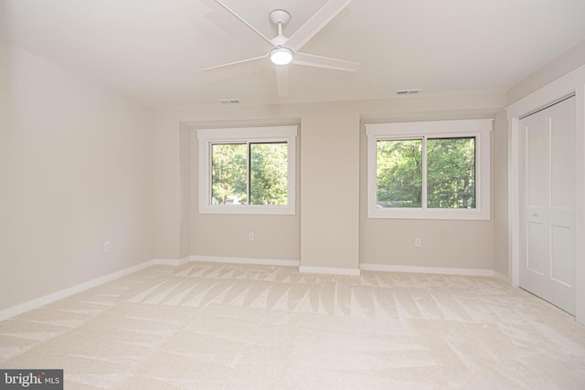 unfurnished room featuring light carpet, a healthy amount of sunlight, and ceiling fan