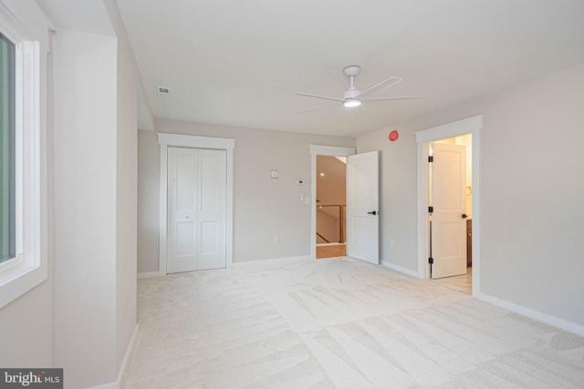 unfurnished bedroom featuring light colored carpet, a closet, and ceiling fan