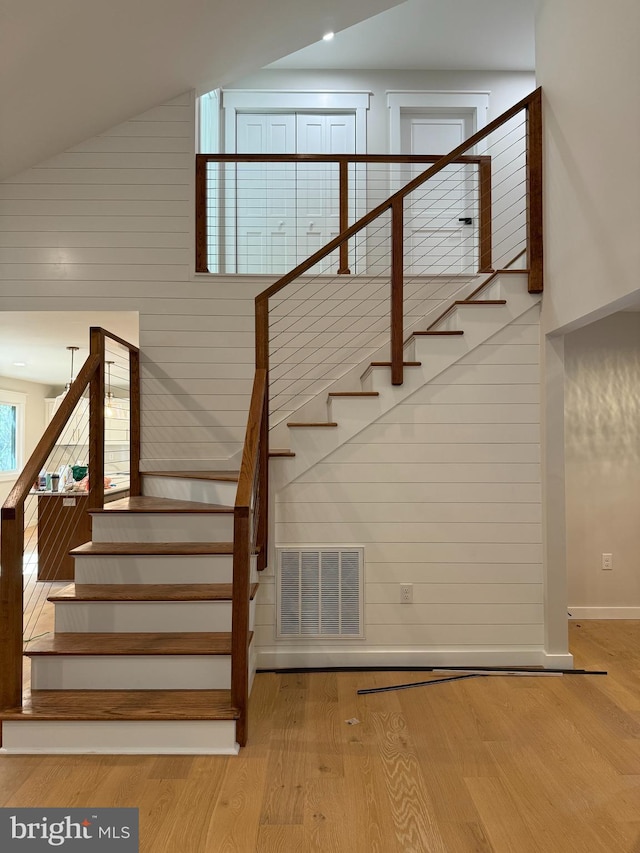 stairs featuring lofted ceiling, hardwood / wood-style flooring, and wooden walls