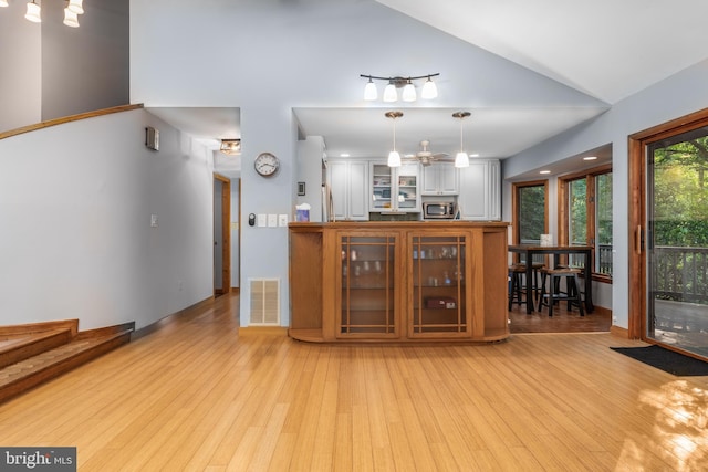 interior space featuring light wood-type flooring, lofted ceiling, and decorative light fixtures