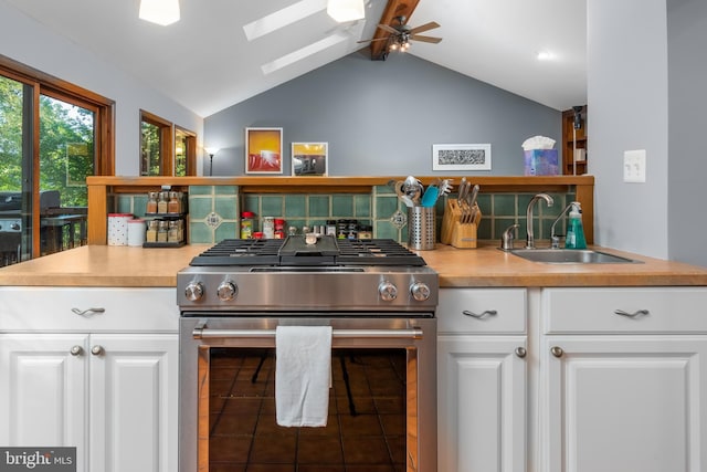 kitchen with white cabinets, lofted ceiling with skylight, high end stove, and sink