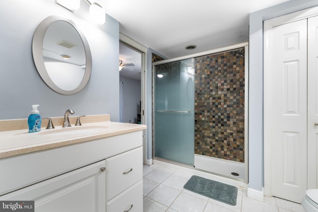 bathroom with a shower with shower door, vanity, tile patterned flooring, ceiling fan, and toilet