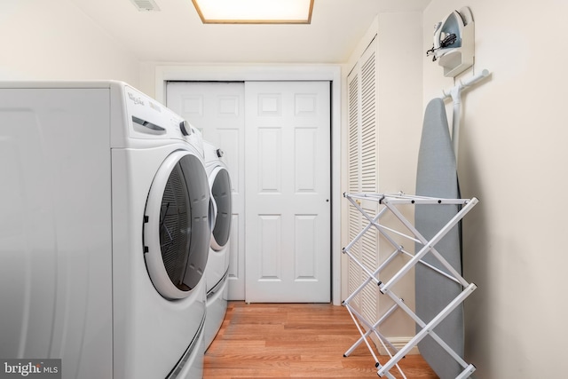 clothes washing area featuring light wood-type flooring and washing machine and dryer