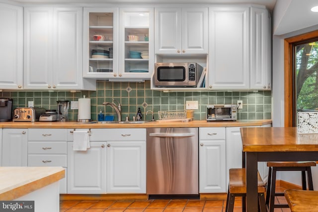 kitchen featuring white cabinetry, tasteful backsplash, light tile patterned floors, stainless steel appliances, and sink