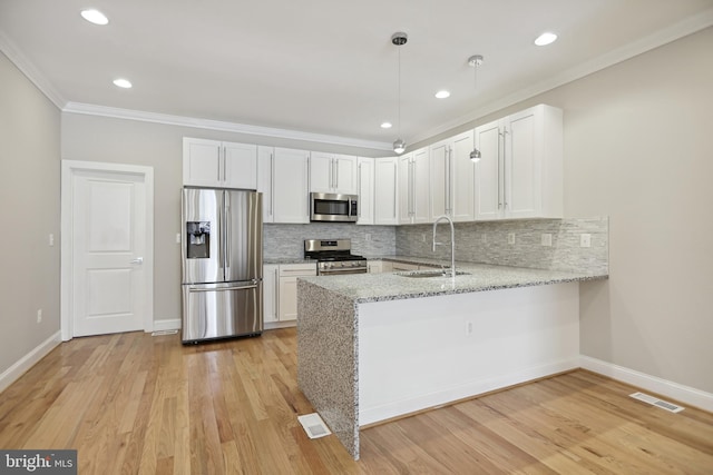 kitchen featuring kitchen peninsula, appliances with stainless steel finishes, sink, and white cabinets