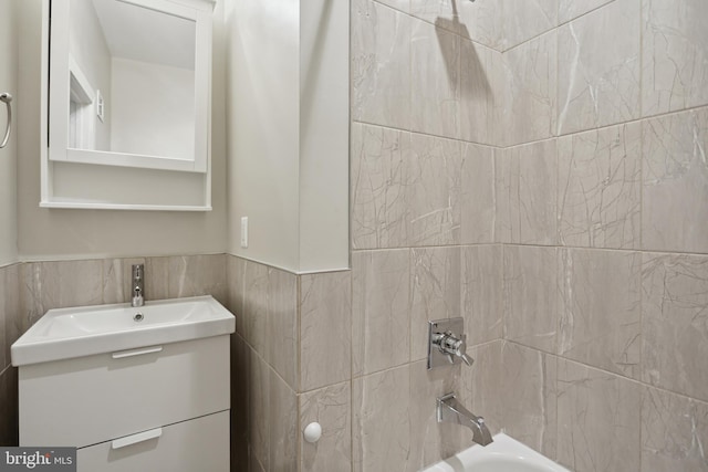 bathroom featuring tile walls, vanity, and tiled shower / bath combo