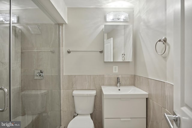 bathroom featuring tile walls, vanity, toilet, and a shower with shower door