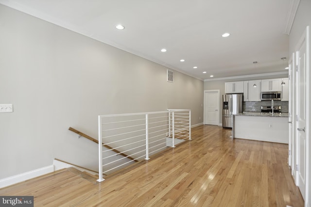 interior space with ornamental molding, light wood-type flooring, and sink