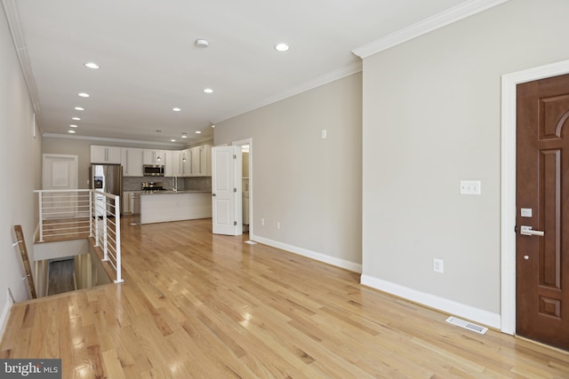 unfurnished living room featuring ornamental molding and light hardwood / wood-style floors