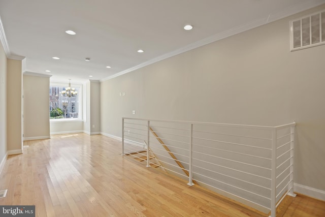 spare room with light hardwood / wood-style flooring, crown molding, and an inviting chandelier