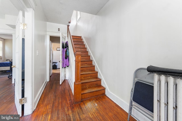 stairway with a textured ceiling and hardwood / wood-style floors