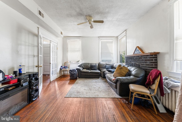 living room featuring a textured ceiling, a fireplace, ceiling fan, and dark hardwood / wood-style flooring