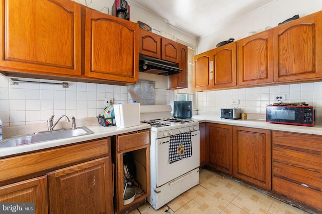 kitchen with white gas stove, sink, decorative backsplash, light tile patterned floors, and crown molding