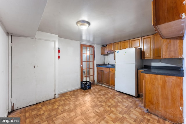 kitchen featuring light parquet floors, sink, and white refrigerator