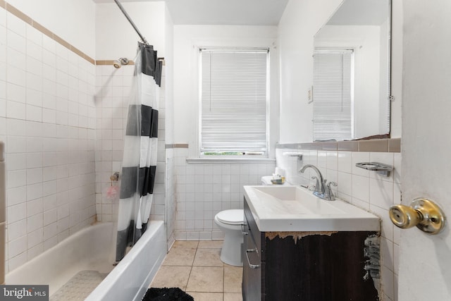 full bathroom with tile walls, shower / bathtub combination with curtain, vanity, tile patterned flooring, and toilet