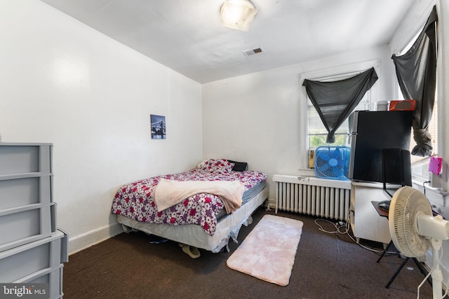 bedroom featuring dark carpet and radiator heating unit