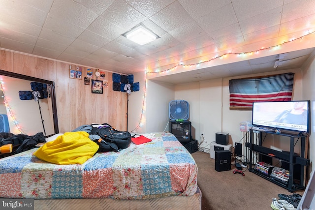 bedroom featuring carpet flooring and wooden walls