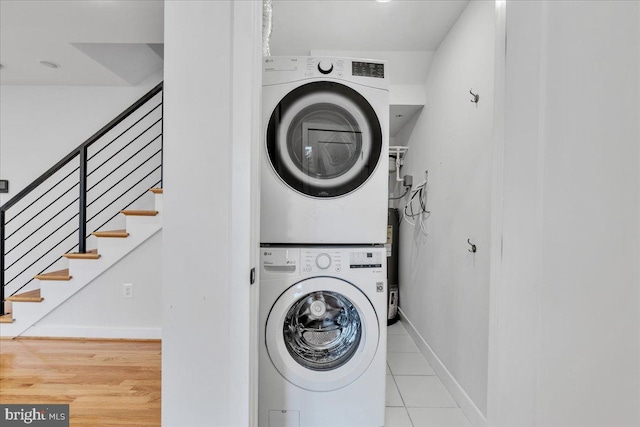 laundry room featuring light wood-type flooring and stacked washing maching and dryer