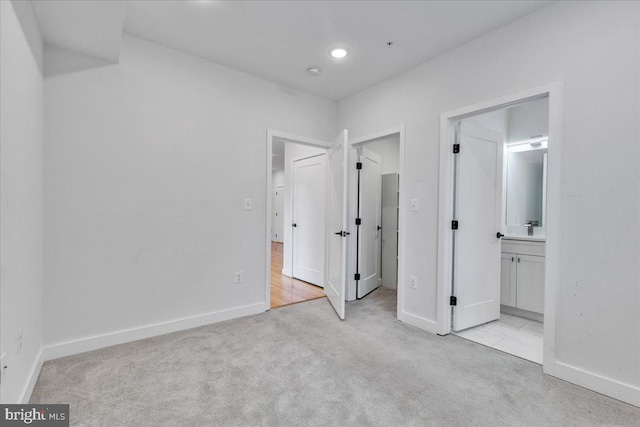 unfurnished bedroom featuring light carpet and connected bathroom