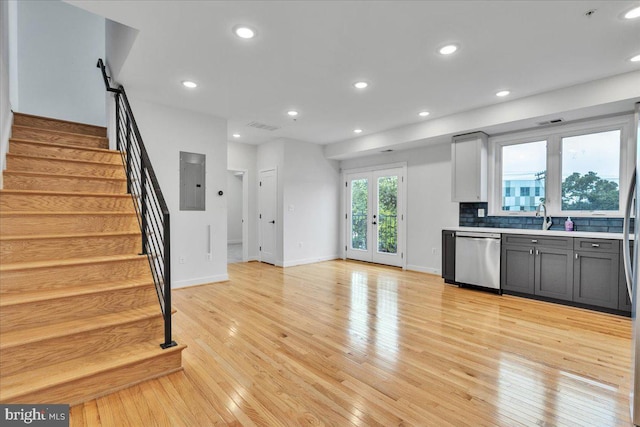 kitchen featuring tasteful backsplash, electric panel, light wood-type flooring, dishwasher, and french doors