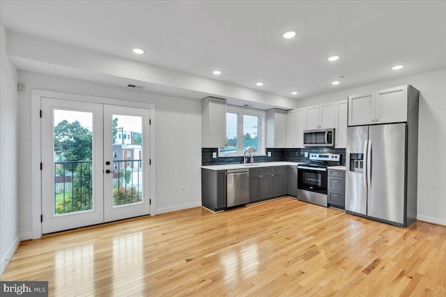 kitchen featuring french doors, stainless steel appliances, decorative backsplash, and light hardwood / wood-style flooring