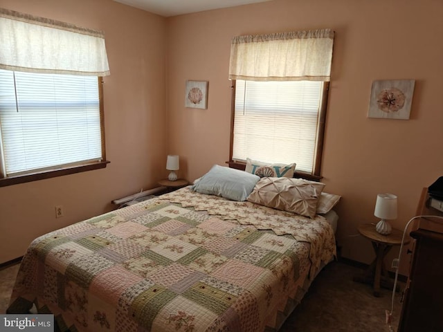 bedroom featuring dark colored carpet and multiple windows