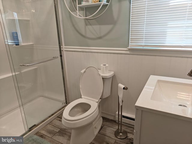 bathroom with vanity, wood-type flooring, walk in shower, a baseboard radiator, and toilet