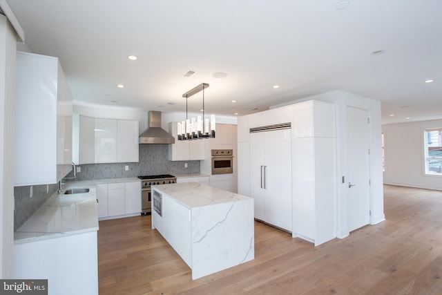 kitchen featuring pendant lighting, high end appliances, white cabinetry, a kitchen island, and wall chimney exhaust hood