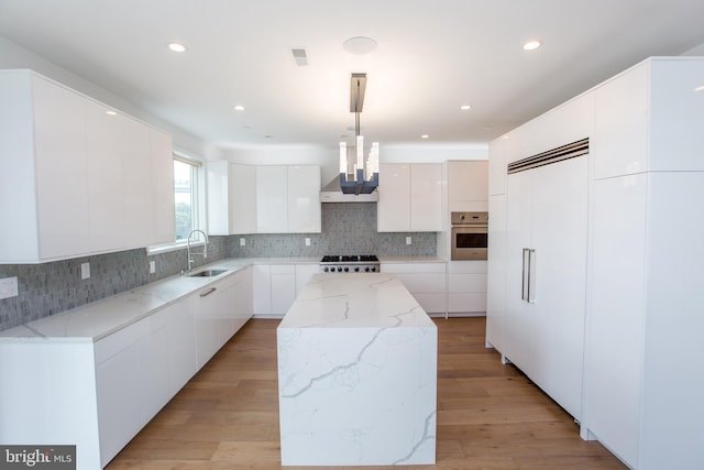 kitchen featuring white cabinets, pendant lighting, light wood-type flooring, oven, and a center island