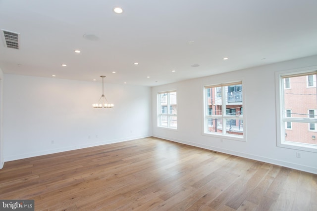 unfurnished room featuring light hardwood / wood-style floors and a chandelier