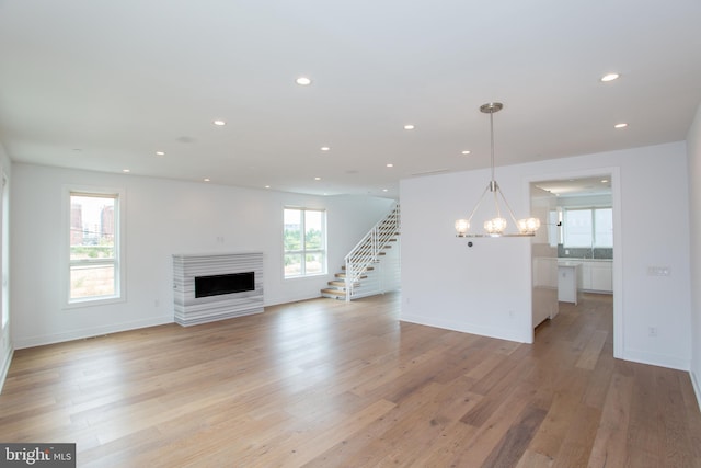 unfurnished living room featuring a notable chandelier, light hardwood / wood-style flooring, and a wealth of natural light