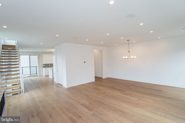 spare room with a notable chandelier and light hardwood / wood-style floors