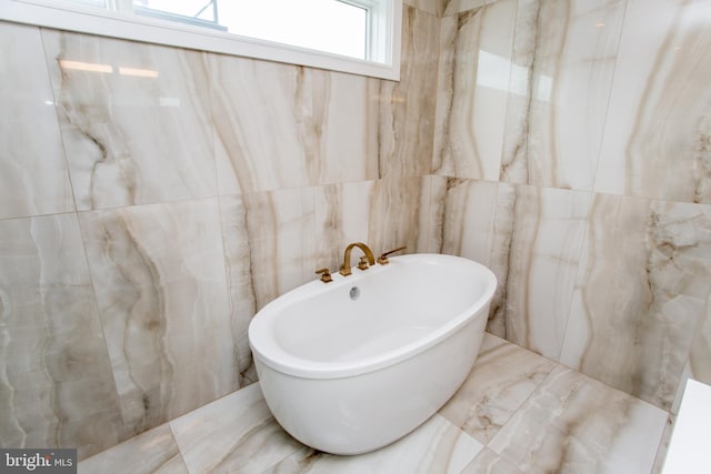 bathroom with a bathing tub and tile walls