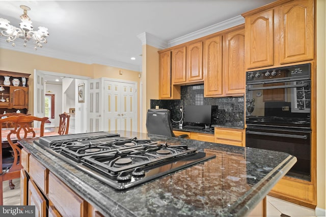 kitchen featuring dark stone countertops, backsplash, gas cooktop, double oven, and a notable chandelier