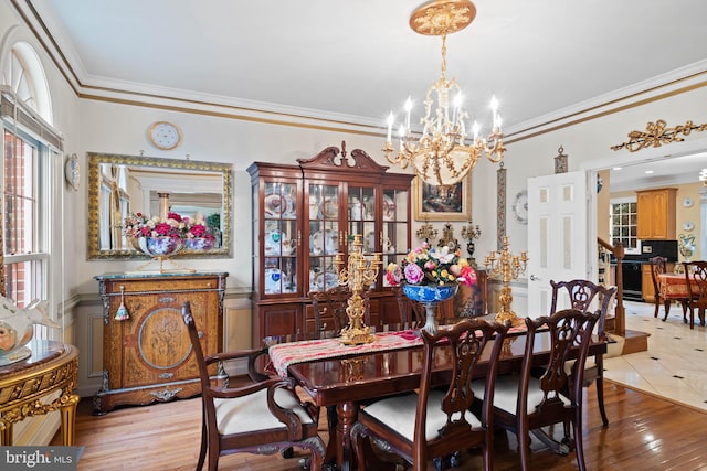 dining room with light wood-type flooring, crown molding, and an inviting chandelier