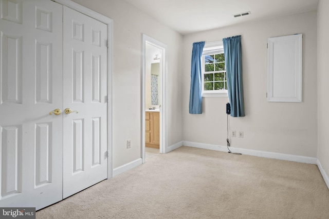 unfurnished bedroom featuring light carpet and a closet