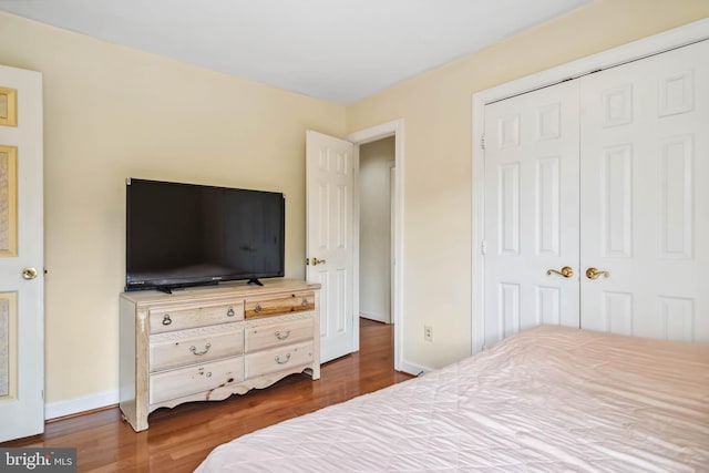 bedroom with dark hardwood / wood-style flooring and a closet