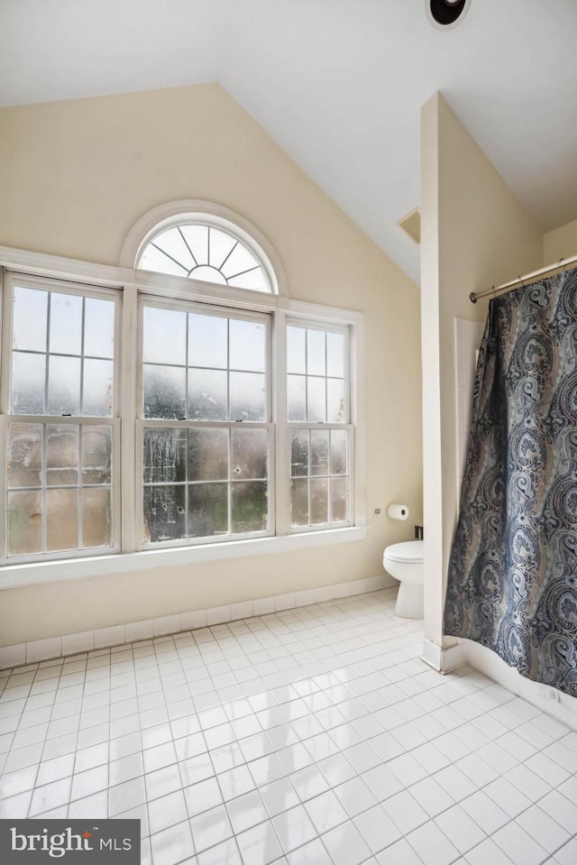 bathroom with tile patterned flooring, lofted ceiling, a shower with shower curtain, and toilet