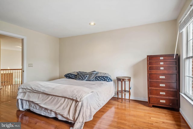 bedroom with light hardwood / wood-style floors and multiple windows