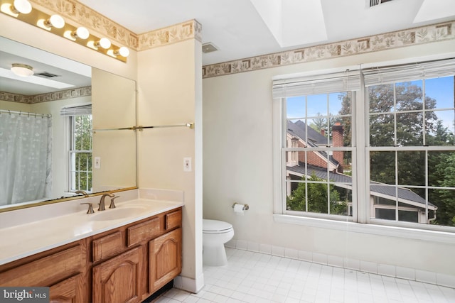 bathroom with vanity, toilet, tile patterned floors, and a wealth of natural light