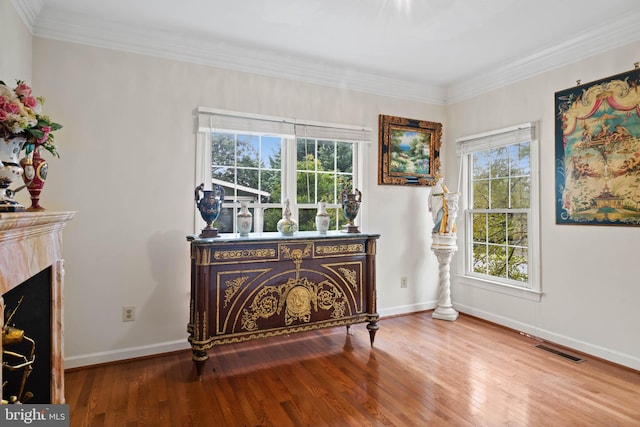 sitting room featuring wood-type flooring, a high end fireplace, plenty of natural light, and crown molding