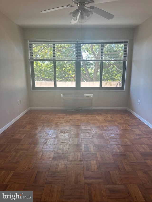 unfurnished room with dark parquet floors, a wall unit AC, and ceiling fan