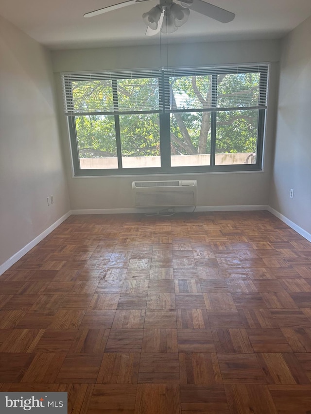 spare room featuring a wall mounted AC, ceiling fan, and dark parquet floors