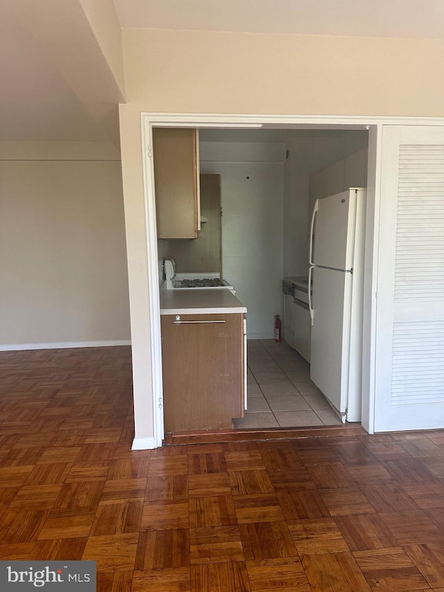 kitchen with dark parquet floors and white refrigerator