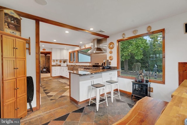 kitchen with island exhaust hood, plenty of natural light, a breakfast bar area, and white cabinets