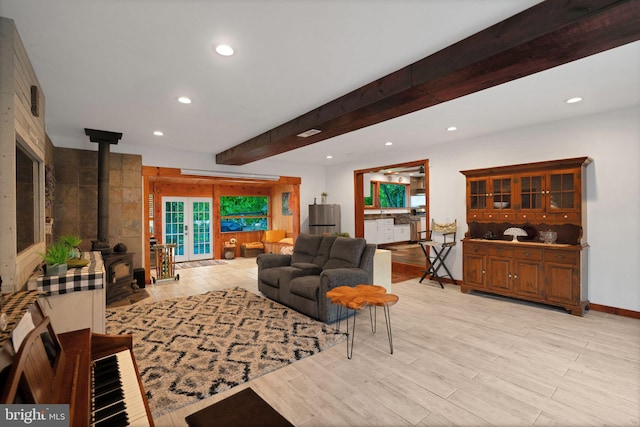 living room featuring beam ceiling, light hardwood / wood-style floors, and a wood stove