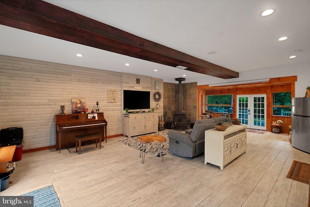 living room with light hardwood / wood-style floors, beam ceiling, and a wood stove