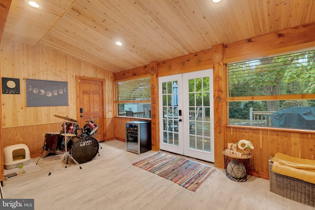 interior space featuring light hardwood / wood-style floors, vaulted ceiling, wood walls, wooden ceiling, and french doors