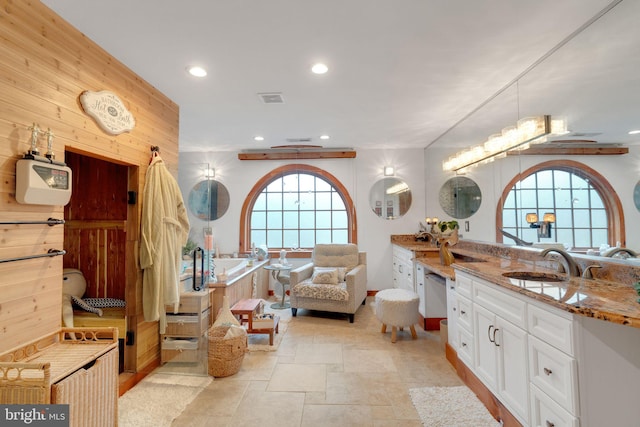 bathroom featuring vanity, plenty of natural light, a tub, and wooden walls