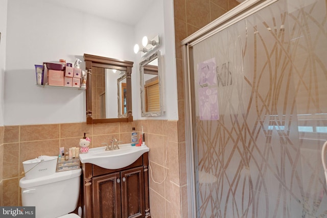 bathroom featuring tile walls, an enclosed shower, vanity, and toilet